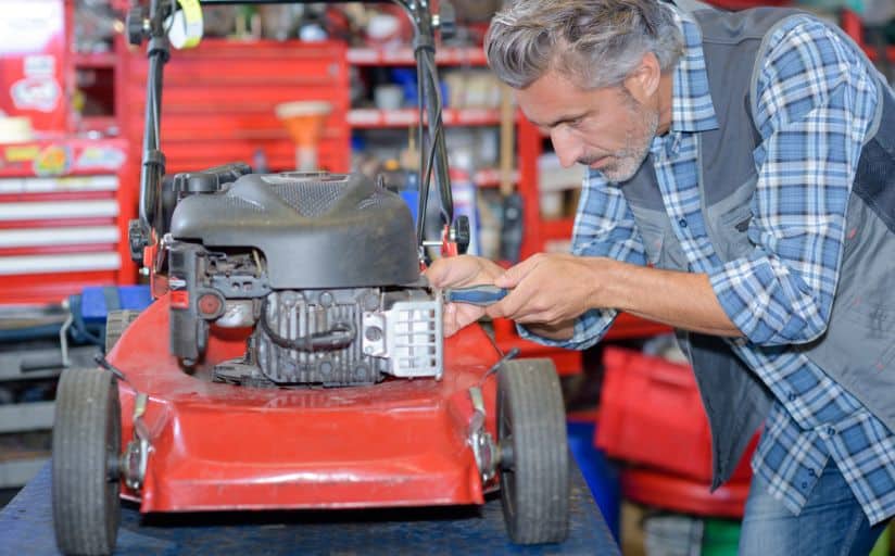 A man maintaining his mower to start cutting his grass in the spring.